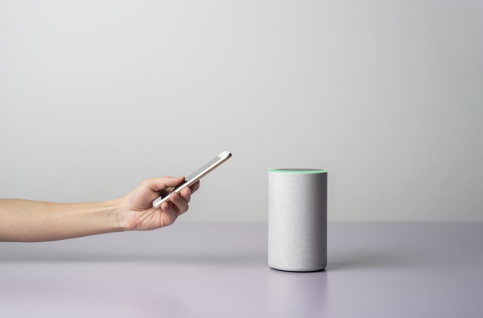 Woman using a Smart speaker with smart phone.