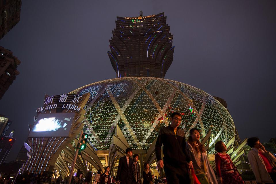 Pedestrians cross an intersection in front of the Grand Lisboa