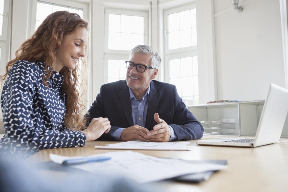 Businessman and woman at desk discussing plans