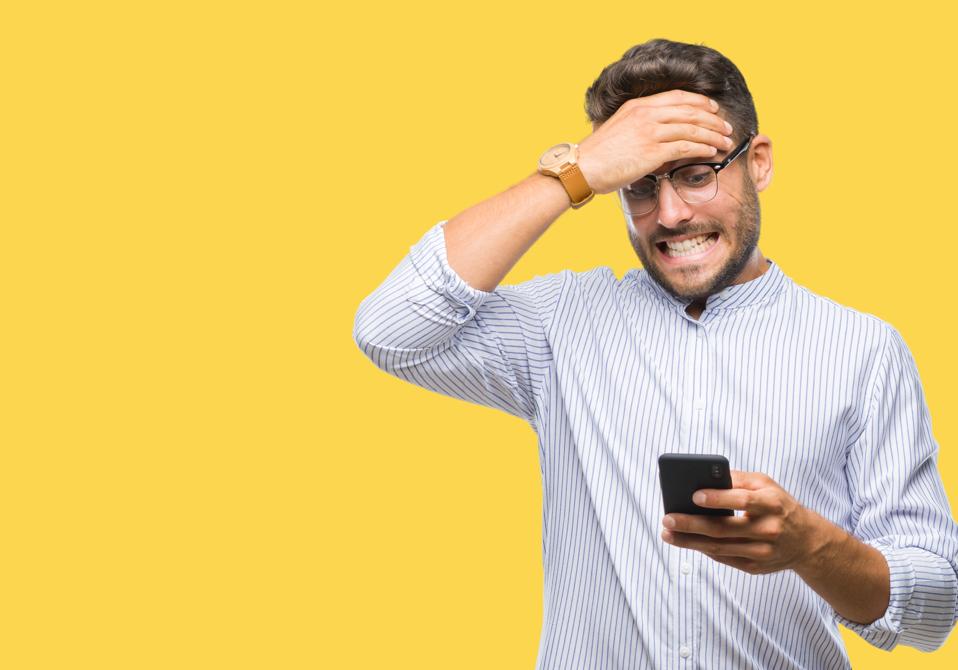 A man is frustrated while looking at his cellphone