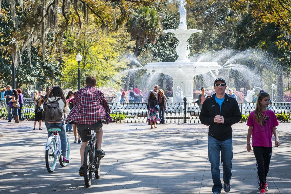 Park with large water fountain and people strolling through