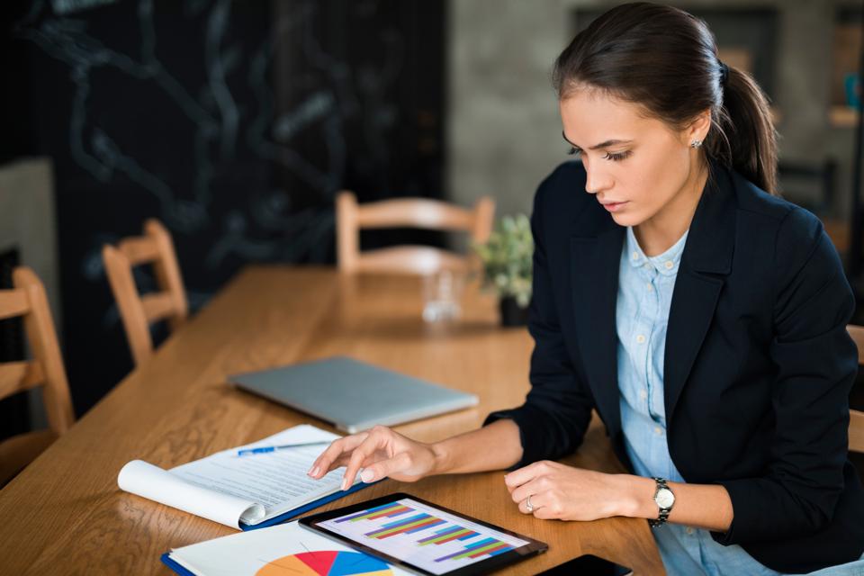 Young businesswoman using digital tablet and analyzing business report.