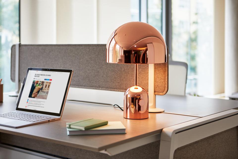Close up of desk with copper-color lamp and open laptop computer