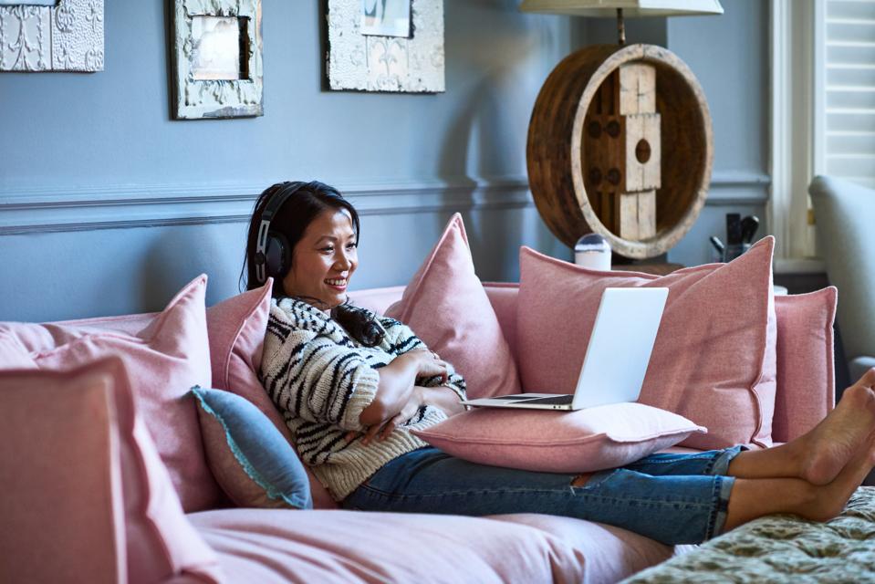 Mid adult woman smiling and watching movie on laptop