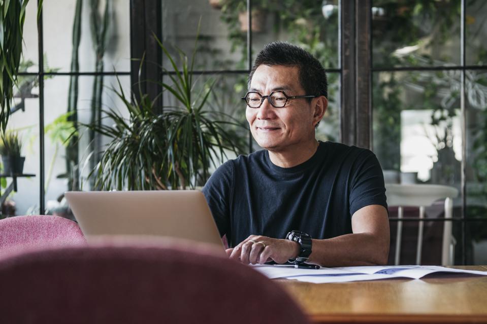 Smiling Chinese man working on laptop at home