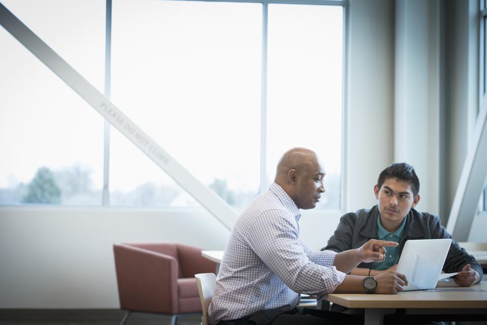 Mentor helping student use laptop