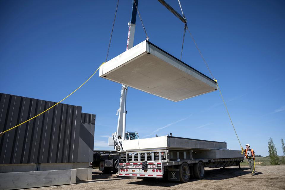 a crane lowers a slab onto a trailer for a Nexii project using Nexiite