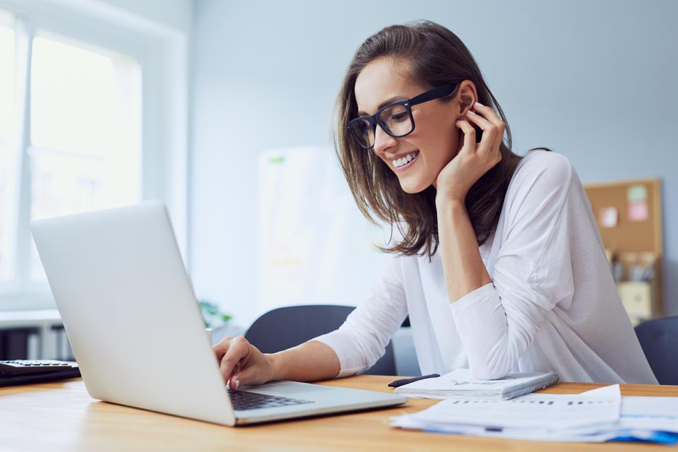 A woman working on a laptop brainstorming ideas for a side hustle with ChatGPT prompts.