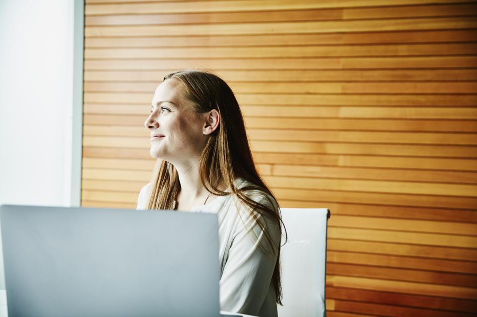 Portrait of smiling businesswoman working on laptop during meeting in office