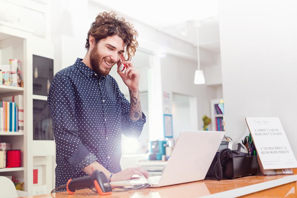 shop owner using laptop and talking on cellphone