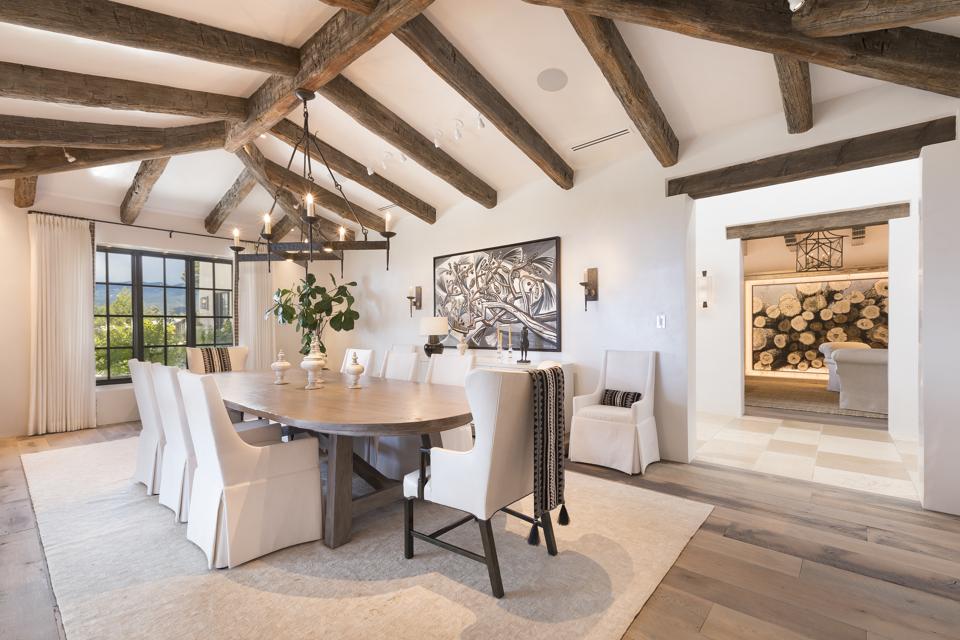 Upscale dining room with white chairs, wood beams on ceiling