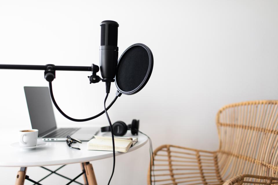 Podcast streaming at home. Audio studio with laptop, microphone with pop filter and headphones on white table.