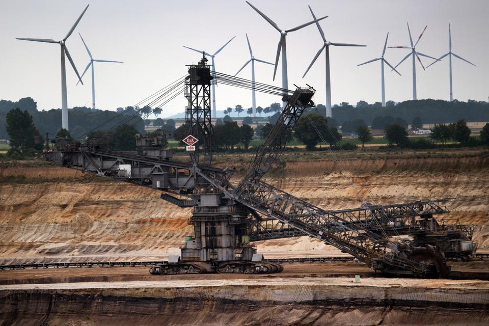 Windmills rotate behind a bucket wheel excavator at a German opencast lignite mine.