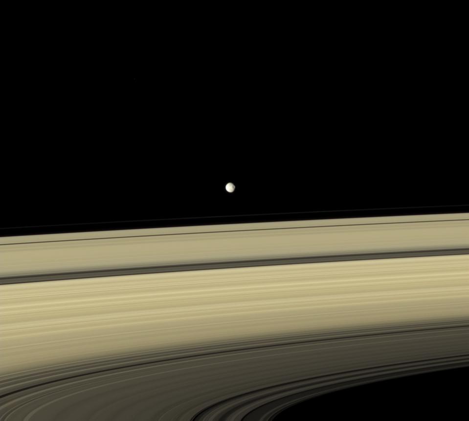 Mimas appears to hover above the colorful rings. Cassini.