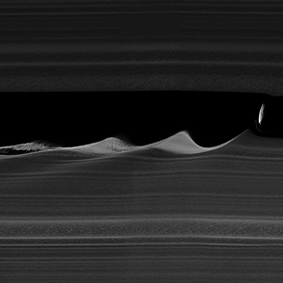 Daphnis within Saturn's main rings, causing ripples and instabilities in the nearby ice.