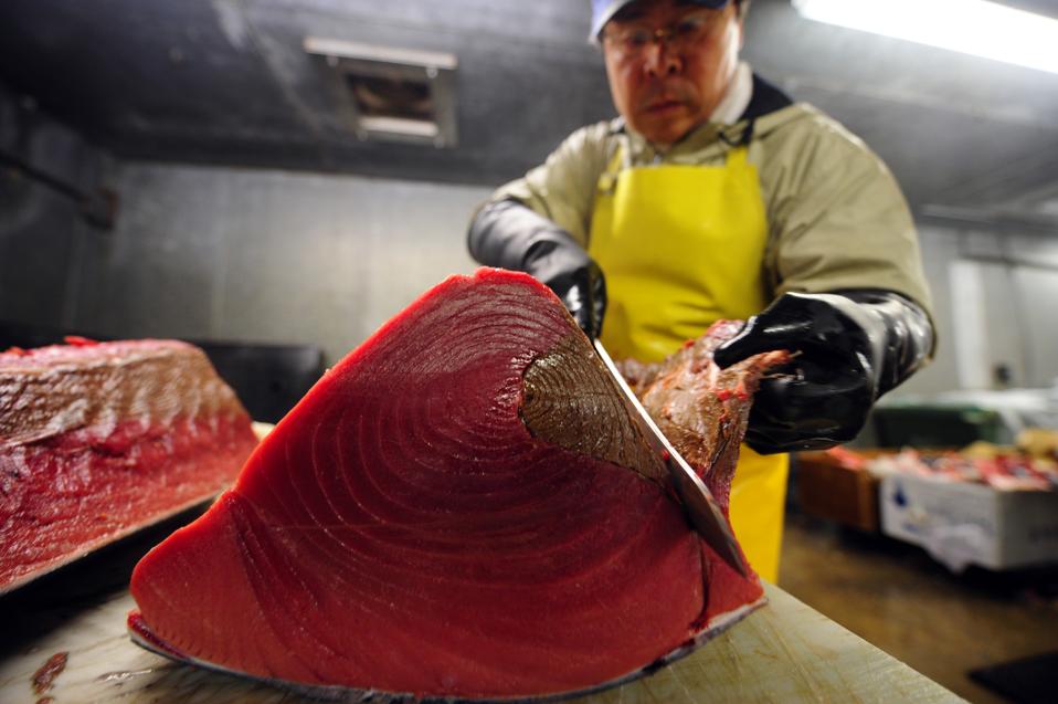 A worker cuts a bluefin tuna into pieces