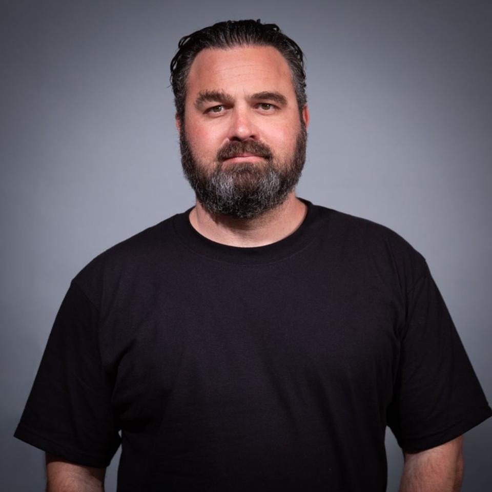 Elliot headshot black t-shirt. beard.