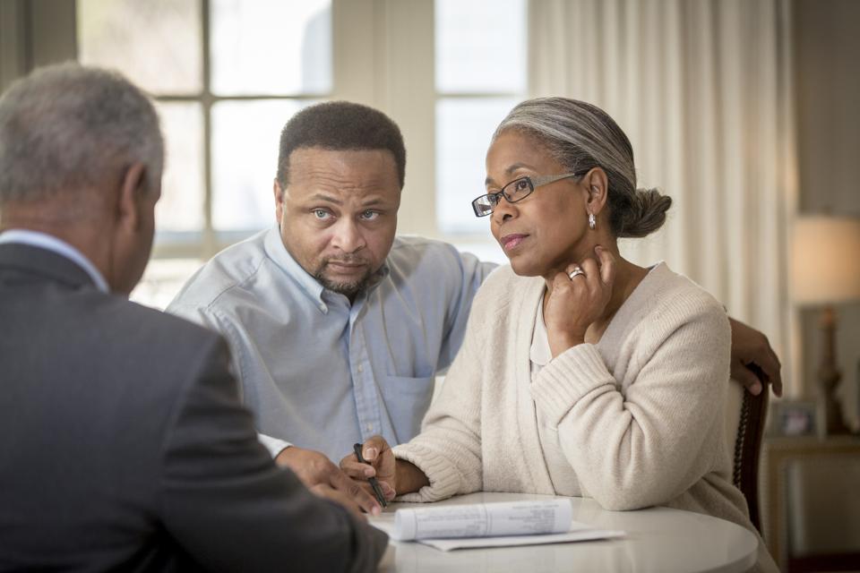 Couple interviewing a financial advisor. Husband concerned.