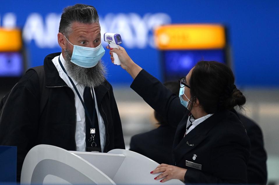 British Passenger wearing face masks has temperature taken at Heathrow UK