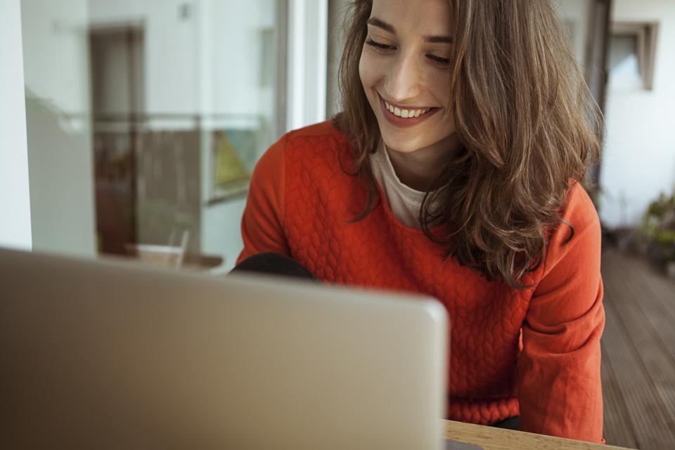 Smiling young woman using laptop on balcony