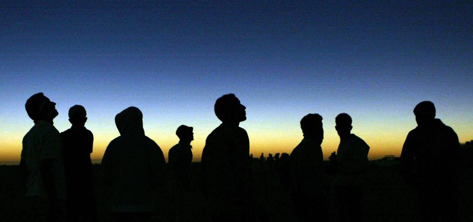 Libyan youths watch the solar eclipse in the desert tourist camp in Galo, 1300 km south of the Libyan capital of Tripoli, 29 March 2006. KHALED DESOUKI/AFP via Getty Images