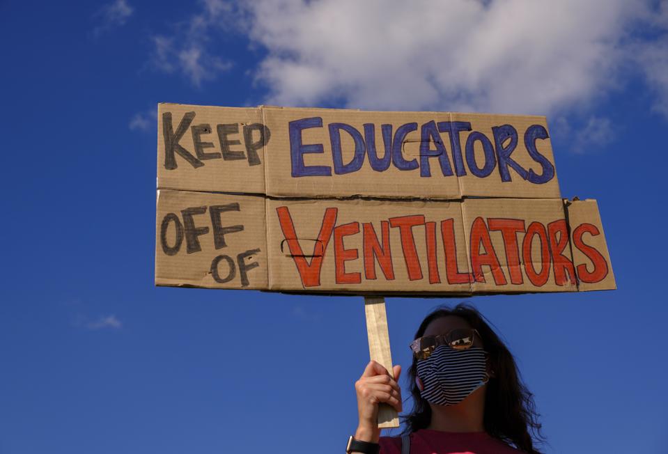 A protester holds a placard that says Keep Educators Off Of...