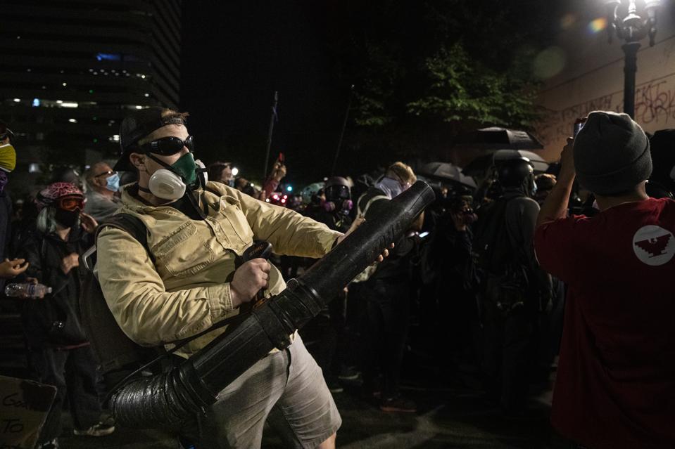 PORTLAND, OR - JULY 25:  A protester uses a leaf blower to dire