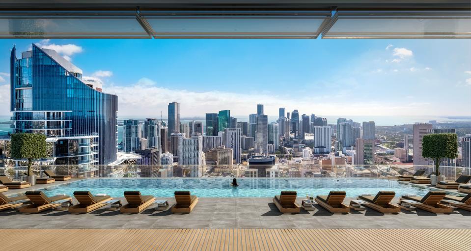 A rooftop infinity pool overlooks a city skyline.