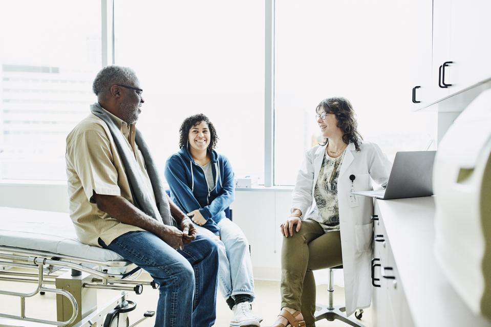 Smiling female doctor consulting with senior male patient et adulte fille dans la salle d'examen