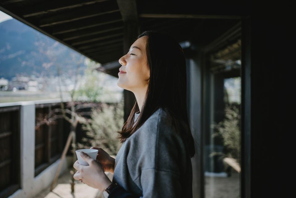 Young woman drinking coffee and enjoying fresh air on balcony in the morning