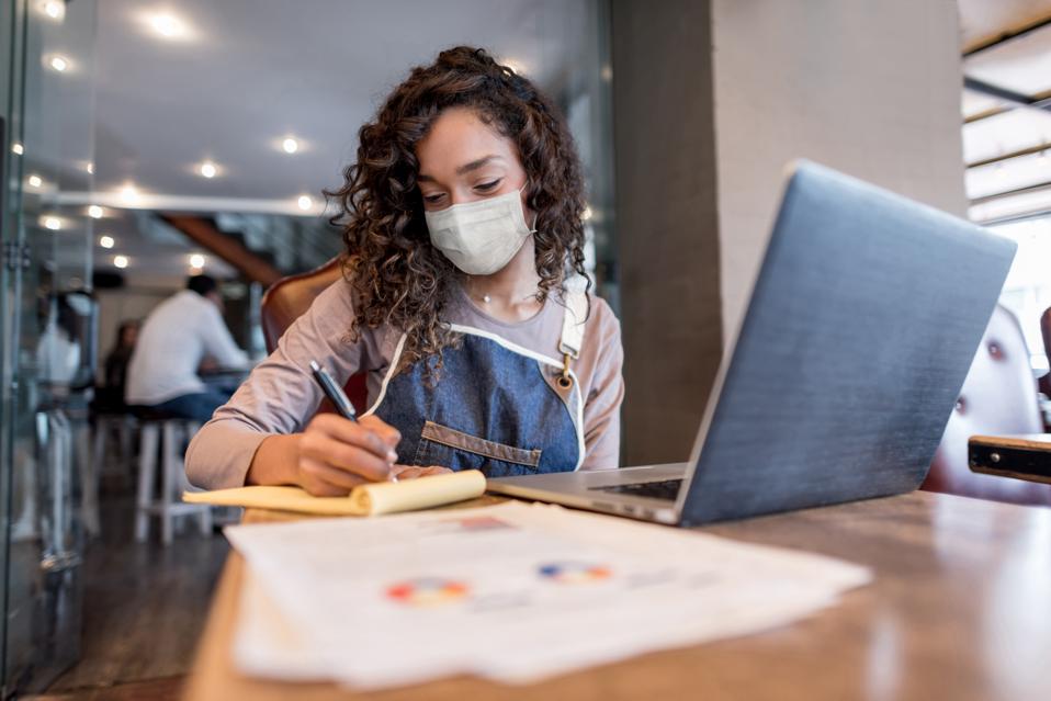 Business manager doing the books at a restaurant wearing a facemask
