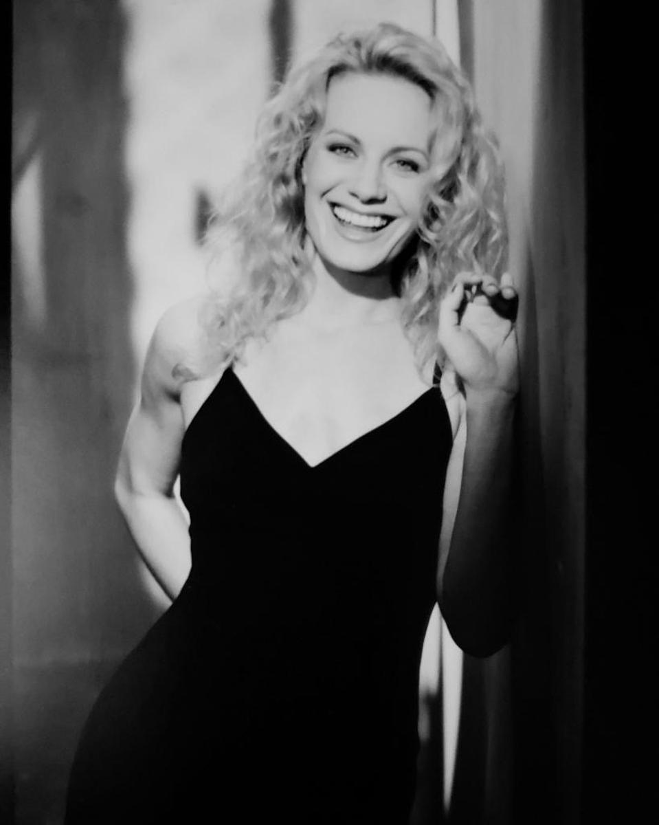 A young Eileen Grubba poses in a black dress.
