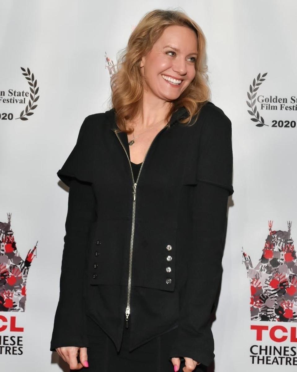 Eileen Grubba, wearing a black shirt and pants, poses for a photo at a festival.