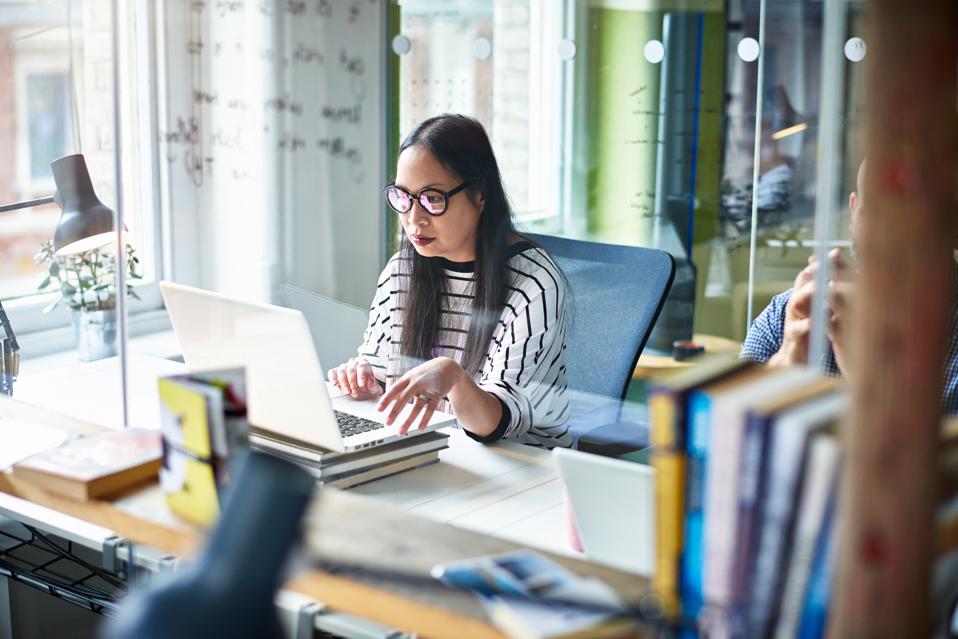 Woman using laptop at desk.