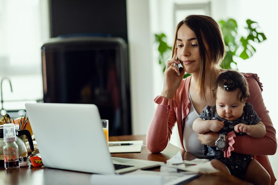 Remote working has created huge challenges for employees as this young mother talks on the phone, uses her laptop and cares for her child.