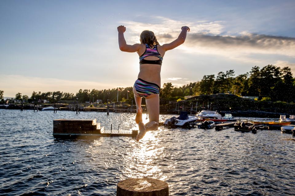 A girl jumps into the Oslo fjord as the sun sets in Norway as Covid lockdown eases