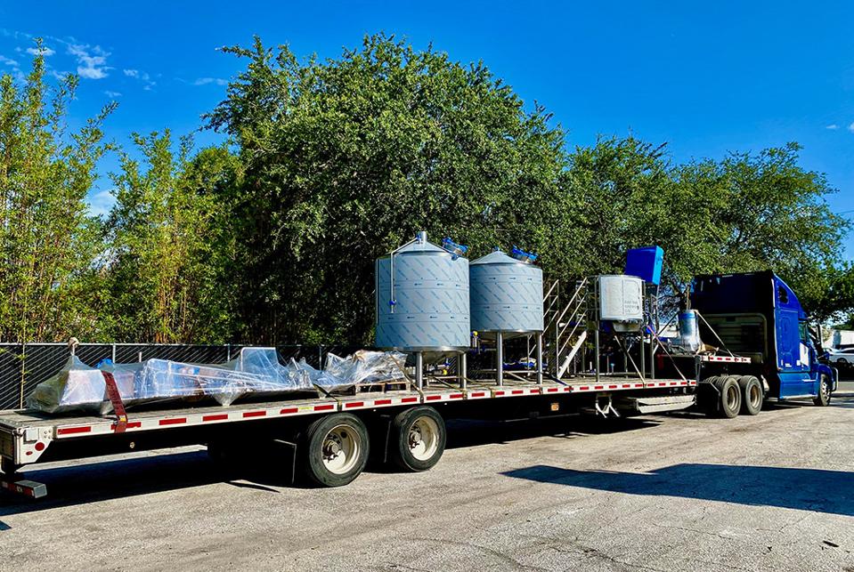 A truck coordinated by Brew Movers shipping logistics carries equipment used to make beer