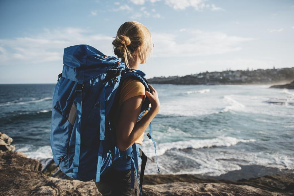 Young female backpacker by the cliff enjoying breathtaking view.