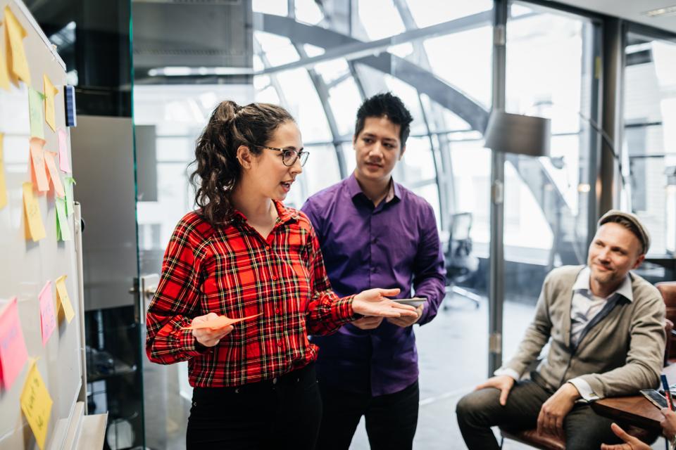 Office Manager Using Sticky Notes On Whiteboard During Meeting