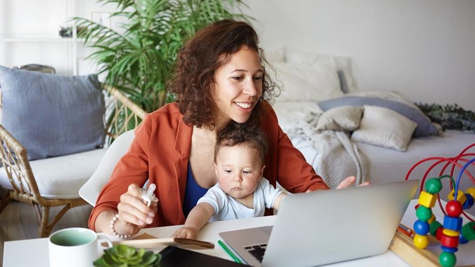 woman working at home on laptop with baby