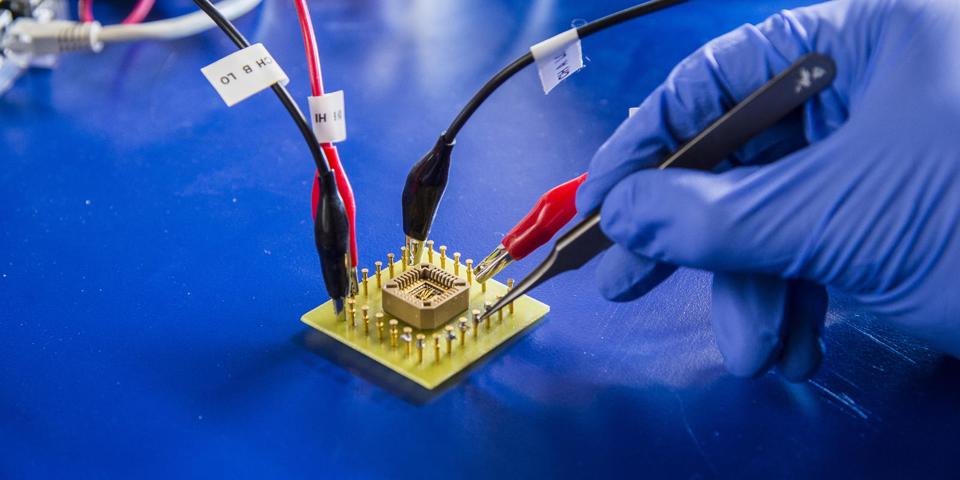 Una mano enguantada en un laboratorio probando un microchip