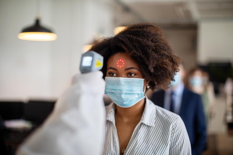 Femme passant par un contrôle de température avant d'aller travailler au bureau