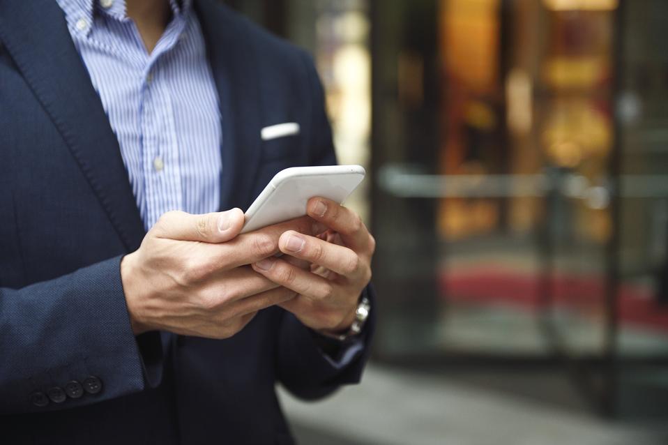 Hands of a man wearing a suit with a smart phone
