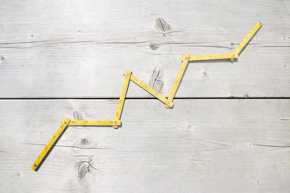 High angle view of a yellow folding ruler in shape of a stock curve on wooden background