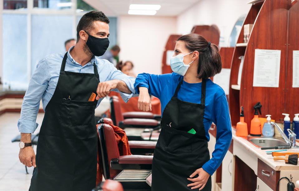 Hairdressers in hairdressing studio practicing alternative greeting for safety and protection during COVID-19