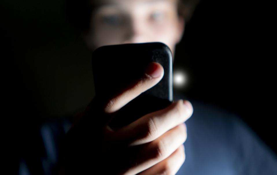 Young man using phone in dark