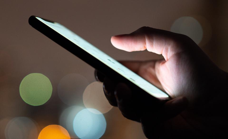 Finger touching smartphone touchscreen at night