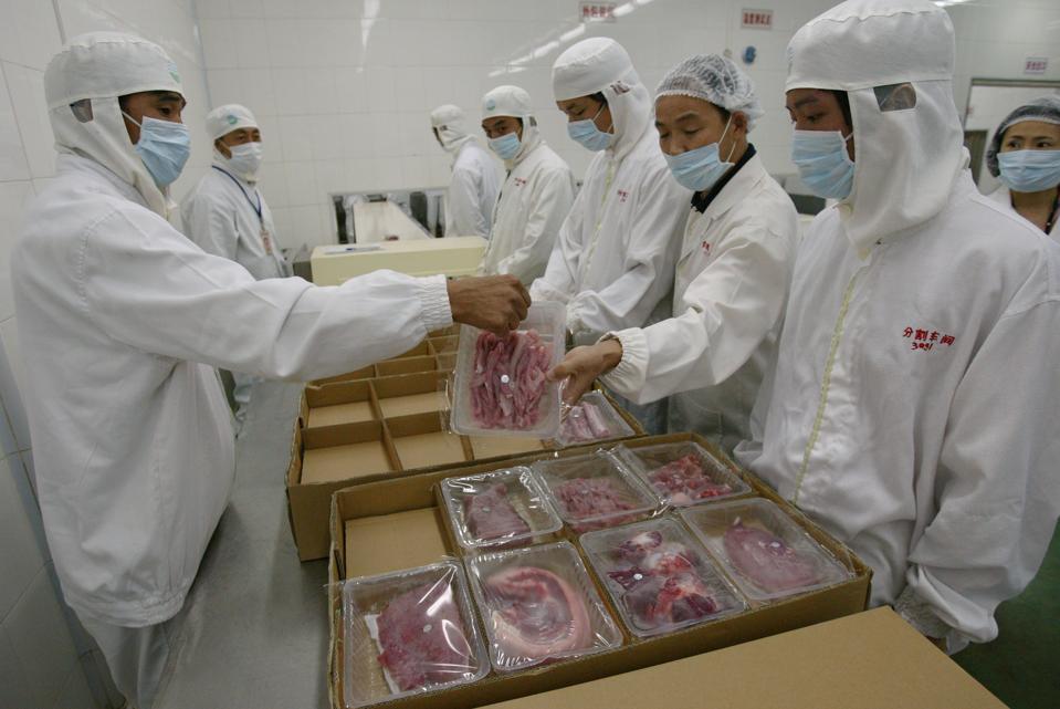 Workers of Dongjin Frozen Meat Co Ltd in protective clothes process the slaughtered pigs (in the packing section) in the frozen pork plant in Huidong, Guangdong, during a media tour by supermarket chain Wellcome. 16 August 2006