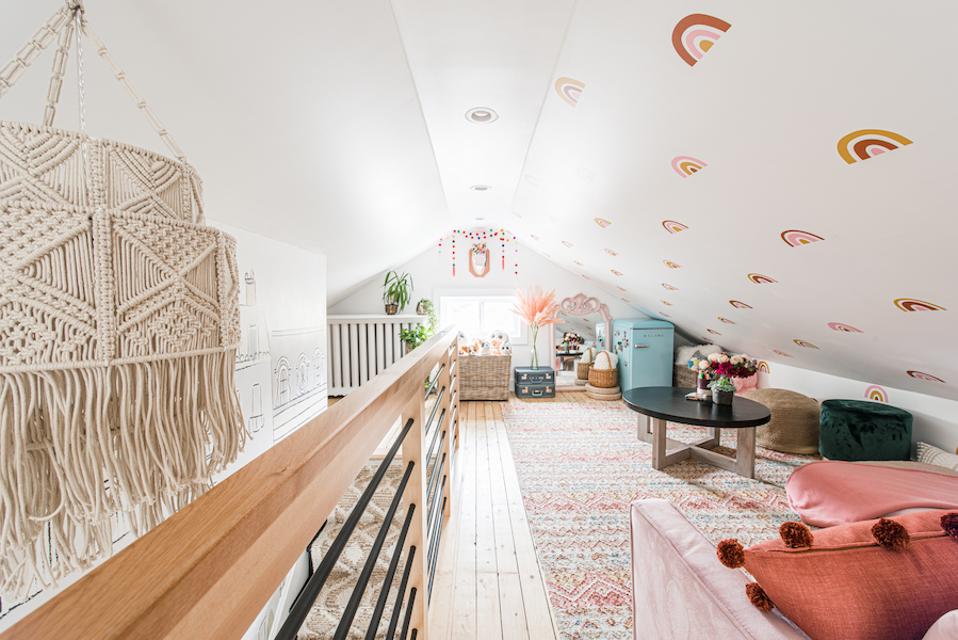 An attic with rainbow decals, a dream catcher and sofas.