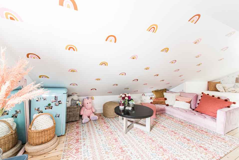 A sloped ceiling area with a lavender sofa, stuffed animals and a table.